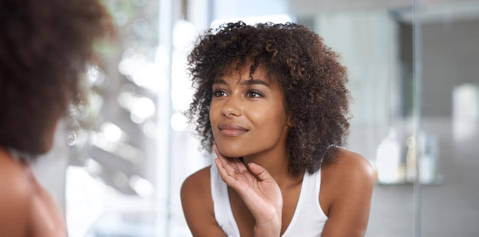 Woman looking at her face in a mirror